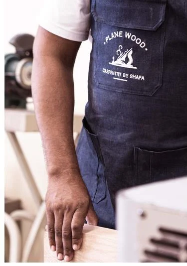 Craftsperson wearing a Plane Wood apron at a woodworking bench